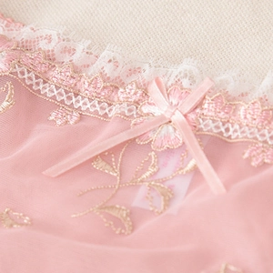 Détail de soutien-gorge en dentelle rose avec broderie florale et petit nœud en soie