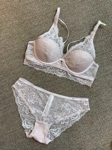 Detailed flat lay of a light pink lace lingerie set with floral bra and sheer briefs