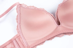 Detailed view of the smooth pink fabric and delicate floral lace edge on a wireless bra