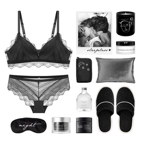 Flat lay of black lace bra set with matching eye mask and lifestyle accessories on white