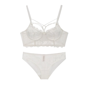 Dettaglio di un set lingerie in pizzo bianco con ricami floreali e design incrociato