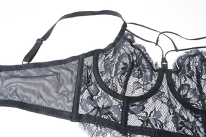Dettaglio macro di lingerie in pizzo blu scuro con motivi floreali e inserti in rete