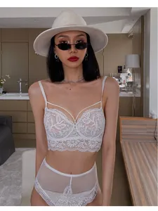 Detailed close-up of a white floral lace bralette set with elegant cross-strap details