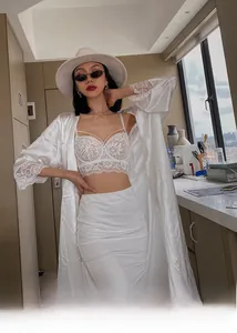 Detail of white lace bra and satin robe showing delicate floral embroidery and texture