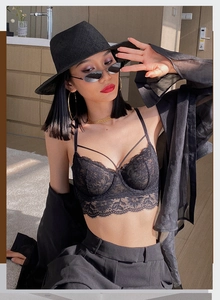 Detail of black floral lace bustier with cross-strap design and scalloped edges