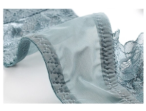 Gros plan sur la dentelle florale bleu-gris avec coutures en zigzag sur un soutien-gorge