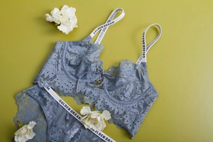 Flat lay of blue lace lingerie set with lettered straps and flower decoration
