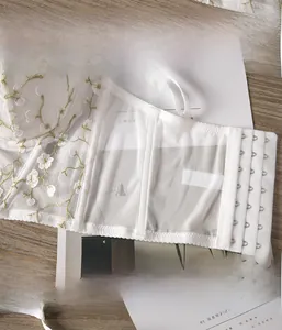 Détail de broderie florale blanche sur soutien-gorge en résille avec baleines et agrafes