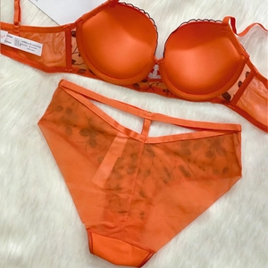 Détail de l'ensemble soutien-gorge en dentelle orange vif avec culotte en maille filet