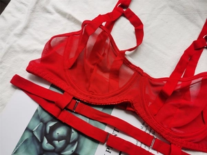 Détail du soutien-gorge en maille rouge avec plusieurs bretelles et boucles métalliques