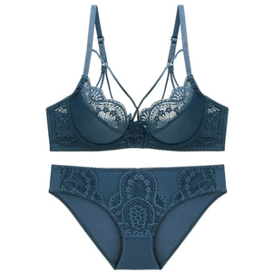 Flat lay of elegant dark blue lace lingerie set with intricate cross straps and floral pattern