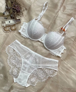Détail à plat d'un ensemble de lingerie en dentelle blanche sur fond de soie élégant