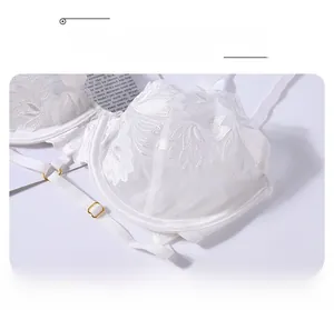 Detail of white lace embroidery and floral texture on underwired bra with gold buckle