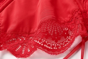 Detailed close-up of red floral lace embroidery and silky fabric on lingerie set