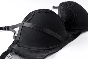 Dettaglio ravvicinato del reggiseno in pizzo nero con ricami floreali e nastri di raso