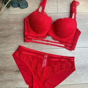 Ensemble de lingerie en dentelle rouge avec anneaux en métal sur fond de bois clair
