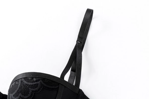 Dettaglio del raffinato pizzo nero e della spallina regolabile su un reggiseno a balconcino