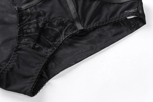 Dettaglio di rete nera trasparente e pizzo floreale su slip di lingerie da donna