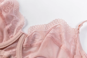 Close-up of delicate floral lace and breathable mesh fabric on pink sexy lingerie