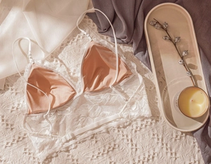 Detail of white floral lace triangle bra with adjustable straps on soft textured surface