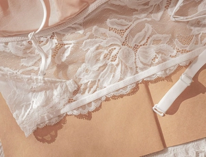 Detailed macro view of white floral embroidery lace and adjustable thin shoulder straps