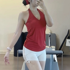 Detail of red halter V-neck yoga top with white drawstring shorts in pilates studio