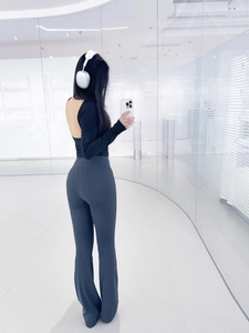 Detail of high-waisted flared yoga pants and backless long sleeve sports top in a studio