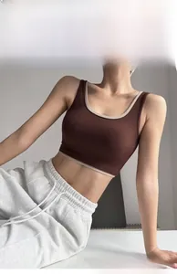 Detail view of brown high-impact sports bra with cream contrast trim on model