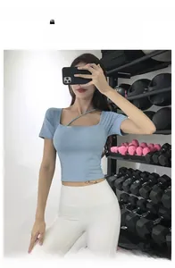 Detail of light blue slim-fit yoga top with asymmetrical neckline in a gym setting