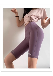 Gros plan du short de yoga violet à taille haute avec imprimé lettres et coupe moulante