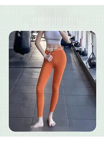 Détail du pantalon de yoga taille haute orange vif avec tissu élastique galbant