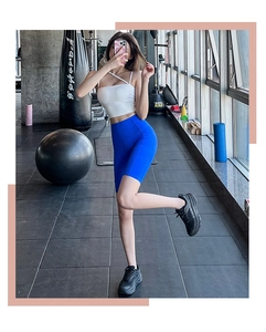 Détail d'un short de yoga bleu taille haute et d'un débardeur blanc en salle de sport