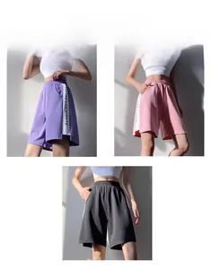 Détail de shorts de sport amples à taille haute avec bandes latérales en violet, rose et noir