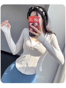 Détail d'une veste de yoga ajustée avec capuche, poignets passe-pouce et fermeture éclair