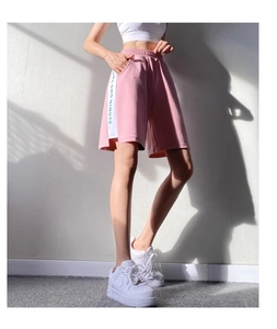 Détail du short de sport rose ample avec bande latérale blanche et lettrage OMG MINUTE