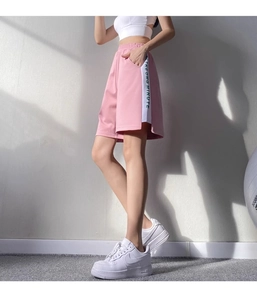 Détail du short de sport rose avec rayures blanches latérales et taille élastique