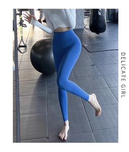 Gros plan d'un pantalon de yoga bleu à taille haute dans une salle de sport équipée