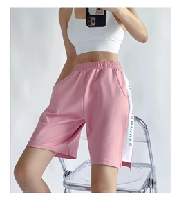 Détail de short de sport rose avec bandes blanches latérales et taille élastique à cordon