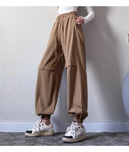 Detail view of khaki jogger pants featuring elastic drawstring waist and pocket details
