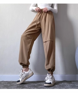 Detail of khaki jogger pants with elastic drawstring waist and knee button accents