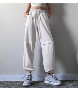 Detailed close-up of high-waist elastic jogger pants with knee button and cargo accents