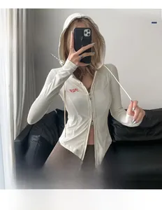Détail de la veste de yoga blanche avec capuche, zip et tissu élastique respirant doux