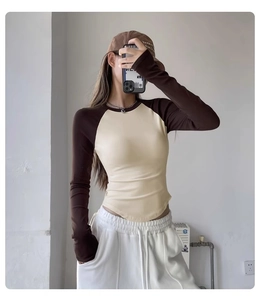 Detail of slim fit raglan long sleeve yoga top featuring contrast beige and brown stitching