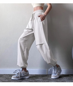 Detail view of cream cargo joggers with elastic drawstring waist and pocket accents