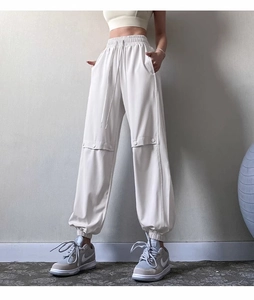 Detail view of cream loose jogger pants with drawstring waist and button knee patches