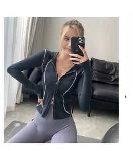 Détail de la veste de yoga noire à capuche avec coutures contrastées et broderie rouge
