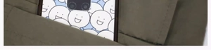 Close-up of a blue phone case with white smiley patterns tucked into a khaki pocket