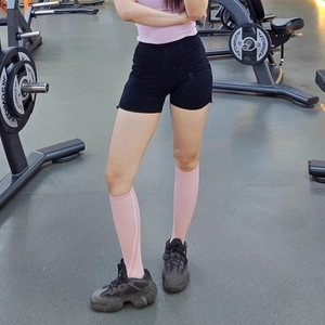 Close-up of pink high-elastic compression calf sleeves with ribbed texture in a gym setting