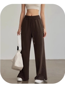 Dettaglio dei pantaloni sportivi ampi color caffè scuro con coulisse e spacco laterale
