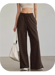 Dettaglio dei pantaloni sportivi marrone scuro con coulisse in vita e spacco laterale